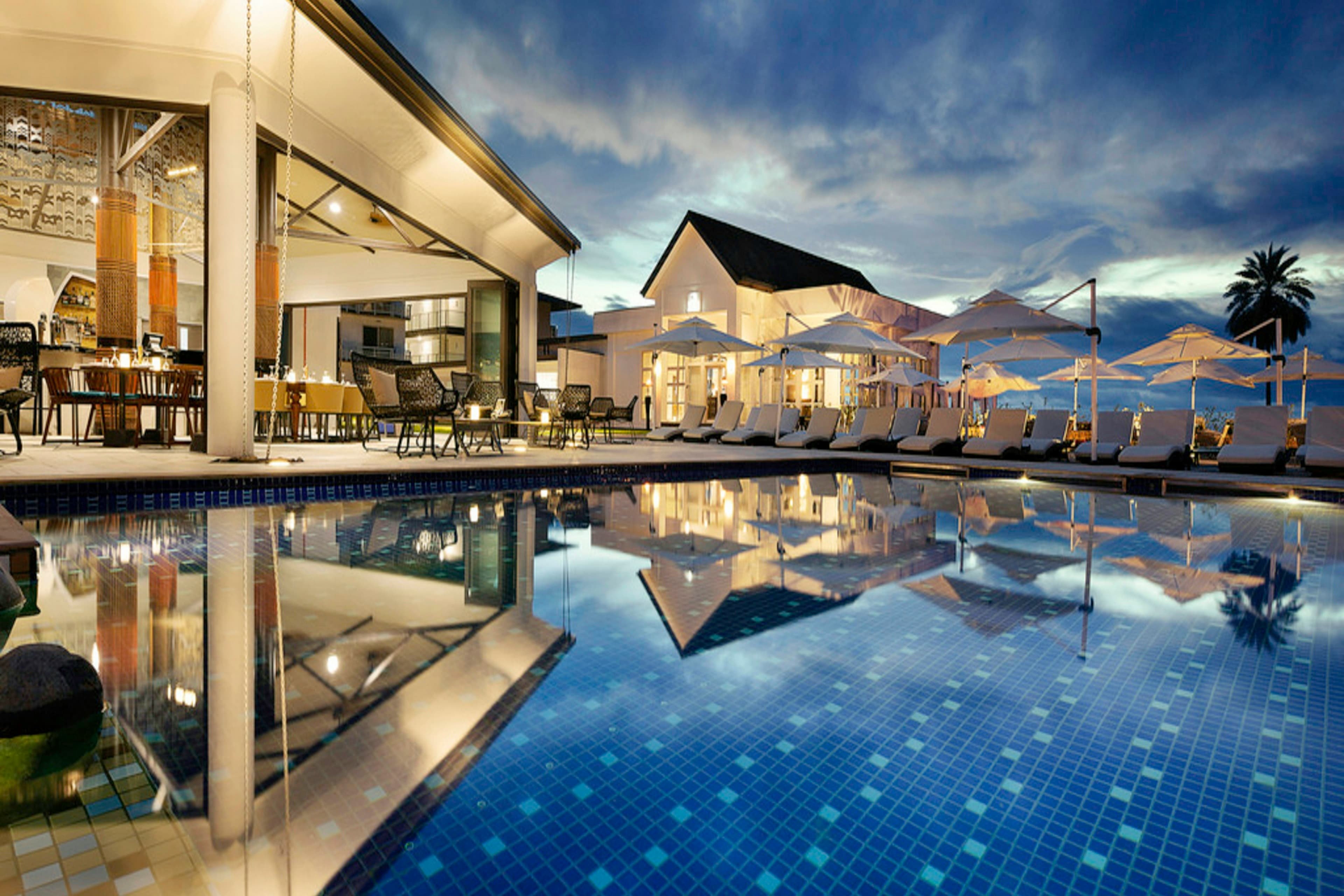 Private island resort pool with tropical palms and polished loungers