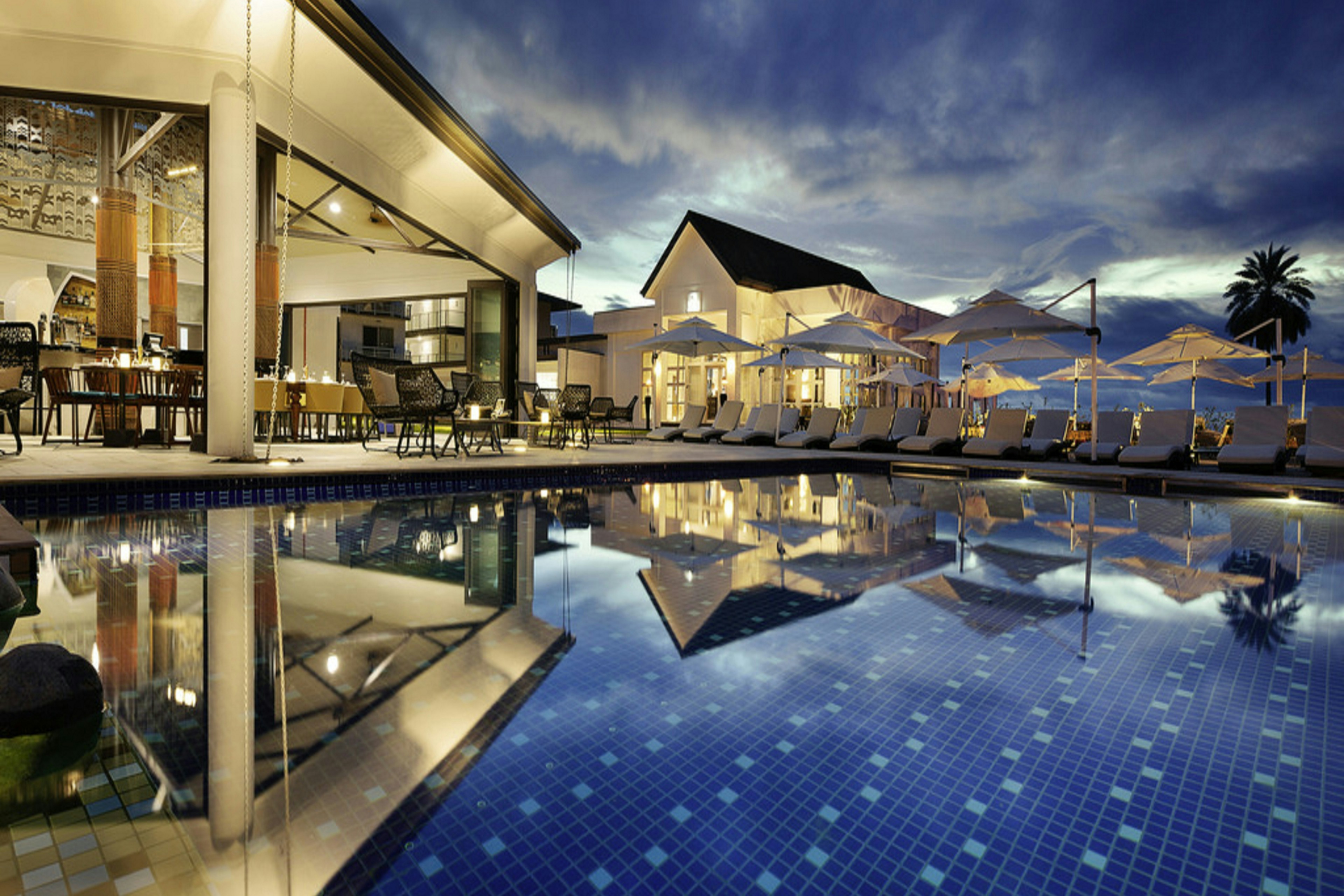Private island resort pool with tropical palms and polished loungers
